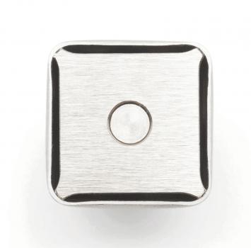 The image shows a square, metallic button. The surface is smooth with a matte texture, and there is a small, round dot in the center. The corners are slightly rounded.