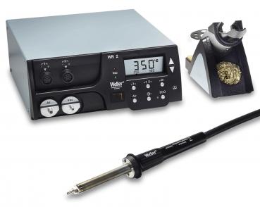The image displays a soldering device with a digital temperature display. Next to the device, there is a soldering iron with a long cable and a soldering station. The predominant colors are grey and black.