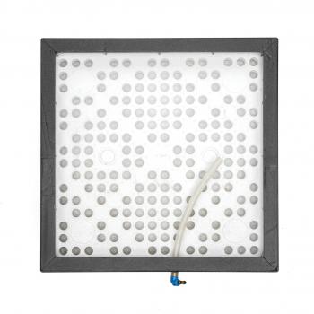 Das Bild zeigt eine quadratische graue Platte mit vielen kleinen runden Löchern. An einer Seite befindet sich ein dünner Schlauch, der herausragt. Die Platte scheint aus Kunststoff zu sein.