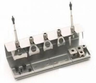 The image shows a metallic tool set with several holders and connections. There are three upright elements and a cable connection that runs sideways. The surface is flat.
