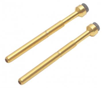 Das Bild zeigt zwei lange, schlanke Objekte aus glänzendem Gold, die oben mit einer kleinen, runden, grauen Spitze enden. Diese Teile wirken wie Werkzeuge oder Industriekomponenten.