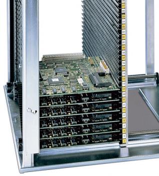 The image shows an open server or computer. Inside, there are several green circuit boards (PCBs) stacked on top of each other, accompanied by silver, vertical cooling fins. The structure is metallic and rectangular.