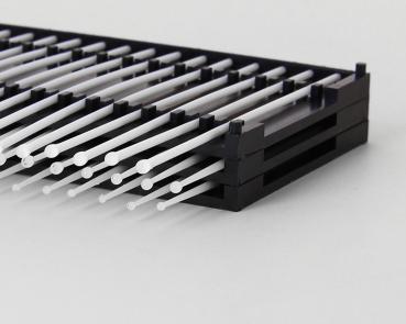 Das Bild zeigt eine schwarze Halterung mit vielen senkrecht stehenden, dünnen, weißen Stäben, die gleichmäßig nebeneinander angeordnet sind. Die Stäbe sind lang und schlank.