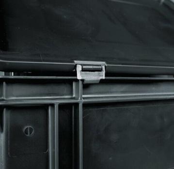The image shows a dark, square plastic container. On the top, there is a clip closure that secures the lid. The bottom has some structural lines and indentations.