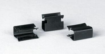 Auf dem Bild sind drei schwarze Metallklammern zu sehen. Sie haben eine ovale Form mit eingekerbten Seiten und einer Öffnung in der Mitte. Die Klammern liegen flach auf einer hellen Oberfläche.