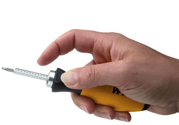 A hand holds a screwdriver with a yellow handle. The tip is slim and made of metallic material. The handle has a non-slip surface.