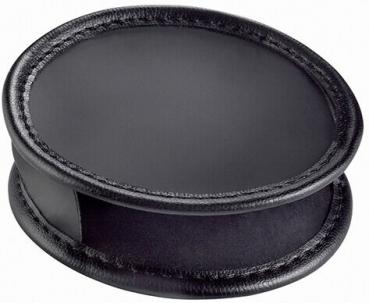 The image shows a round, flat object made of black material. It has a slightly raised edge and an opening on the side. The surface is smooth and shiny.