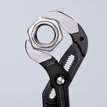 The image shows an adjustable wrench gripping a metal nut. The wrench has black handles and a shiny, silver working surface with sharp edges.