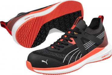 The image displays athletic shoes in black with orange accents. The sole is solid white with a special pattern. On the sides, there are light white stripes visible.