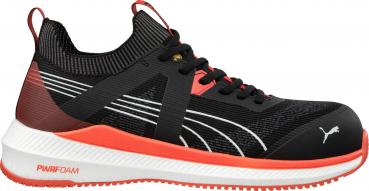 The shoe is black with red accents. It has a low lacing, reinforced sides, and a white sole with special cushioning. The design is sporty and modern.