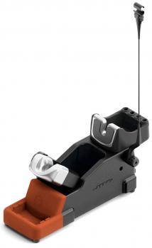 The image shows a ski binding with an orange, compact base and a black mount. At the top are two fasteners securing the ski boot system. A cable protrudes.