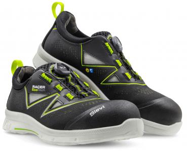 The image shows a pair of black work shoes with green accents. They feature a quick-lacing system and a sturdy, light-colored sole. The text "Racer Eco Tech" is visible.