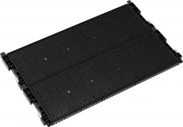 Das Bild zeigt ein schwarzes, längliches Objekt mit parallel verlaufenden Rillen. Es hat zwei seitliche Ausbuchtungen und sieht aus wie ein Teil von Maschinen- oder Fahrzeugequipment.