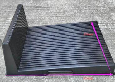 Es handelt sich um eine schwarze, flache Kunststoffplatte mit einer erhöhten Rückwand. Die Oberflächenstruktur ist rutschfest mit parallelen Rillen. Die Maße sind 270 mm hoch und 385 mm breit.