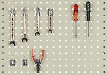 On a perforated panel, various tools are arranged: five wrenches in the top row, below them pliers with red handles, and two screwdrivers on the right side.
