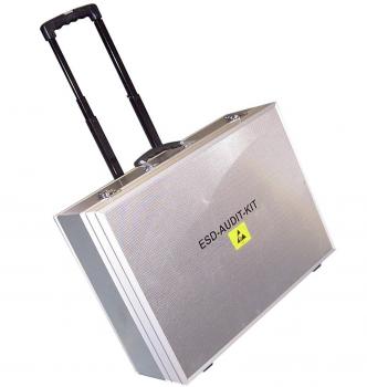 The picture shows a silver suitcase with a telescopic handle, standing on wheels. On the front, the inscription "ESD-AUDIT-KIT" is visible.