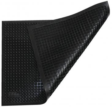 The image shows a black, rubber-like mat with a textured surface. One corner of the mat is folded back, revealing a pattern of small dots and grooves.