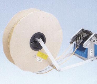 The image shows a large, round roll made of light material, with a mechanism attached to it that includes a motor. A belt connects the roll to the mechanism.