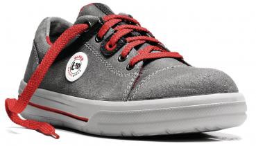 Das Bild zeigt einen grauen Schuh aus Wildleder mit roten Schnürsenkeln. An der Seite befindet sich ein weißes Logo. Die Sohle ist flach und in Weiß mit einem roten Akzent.