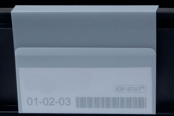 Das Bild zeigt einen weißen Umschlag mit einer transparenten Klappe. Darauf sind Zahlen ("01-02-03") und ein Barcode abgedruckt. Der Hintergrund ist dunkel.