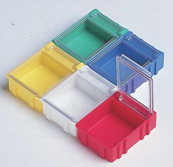 In the picture, there are six small containers arranged in various colors: yellow, green, blue, red, and clear. They are rectangular and open, some have lids. The overall configuration appears geometric.