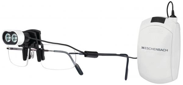 The image shows a special pair of glasses with two small cameras on the top. It is connected to a technical device that is white in color and attached to the right side.