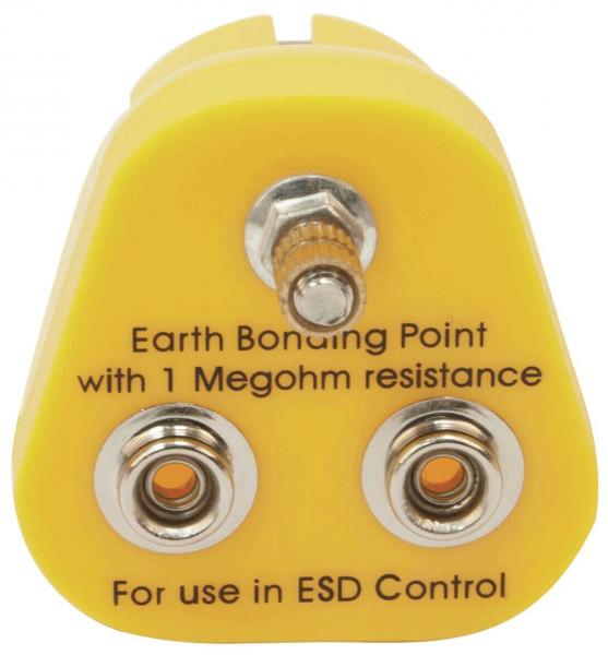 The image shows a yellow plug with a triangular shape. At the top is a screw, below are two round contacts with orange centers. Labeling for grounding and ESD control.