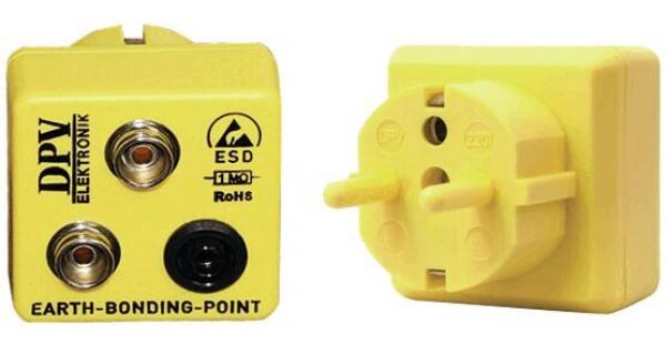 The image shows a yellow adapter with two metallic sockets and a European plug input. Labels indicate grounding and ESD functions.