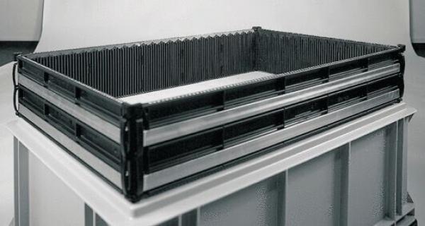 Das Bild zeigt eine schwarze Kunststoffkiste auf einem hellgrauen Untergrund. Die Kiste hat hohe, perforierte Wände und ist rechteckig geformt, mit einem stabilen, strukturierten Design.