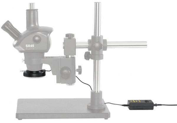 The image shows a microscope with a stable metal base. It has two eyepieces and a stage for the object. Next to the microscope is a control panel with buttons.