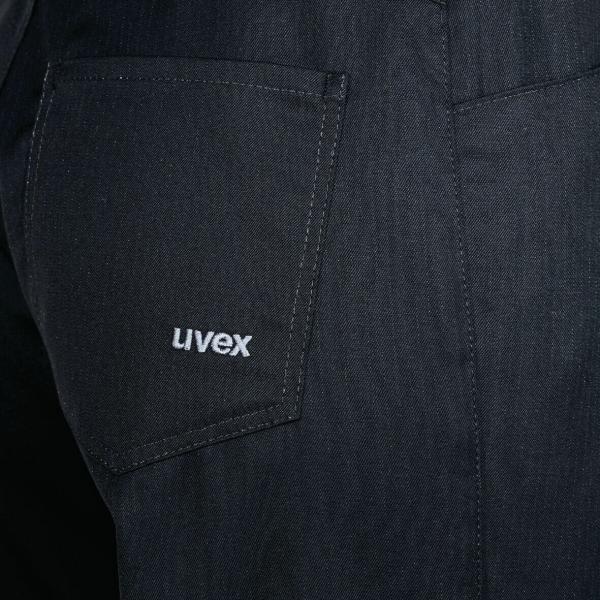 Das Bild zeigt den unteren Teil eines schwarzen Kleidungsstücks, vermutlich eine Hose oder Latzhose. Am linken Hosenbeinteil befindet sich eine aufgesetzte Tasche mit dem weißen Schriftzug ?Uvex?.