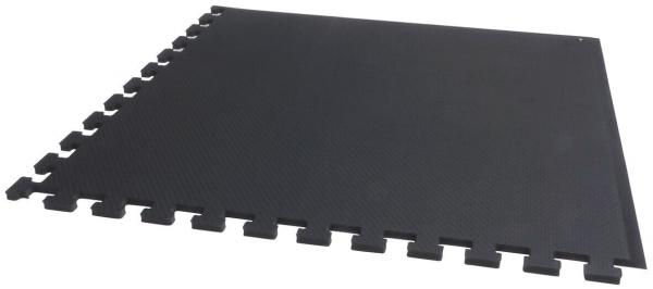 Das Bild zeigt eine schwarze, quadratische Matte mit gezahnten Kanten, die ineinandergreifend angeordnet werden kann. Sie ist aus einer flexiblen, rutschfesten Oberfläche gefertigt.