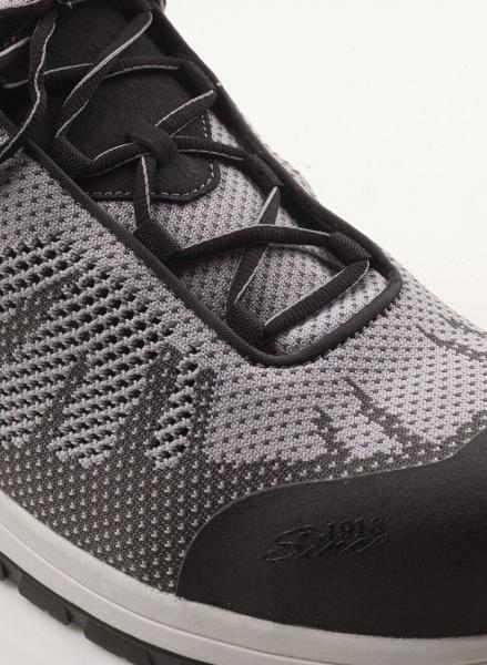 Das Bild zeigt einen sportlichen Schuh in Grau und Schwarz mit atmungsaktivem Netzmaterial. Die Schnürsenkel sind schwarz, und die Sohle ist leicht erhaben.