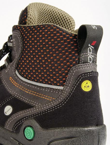 The image shows the upper part of a sturdy shoe. It is made of black material with orange and gray details. The surface is partially made of textured mesh fabric.