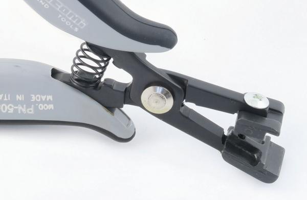 The image shows a gray and black pliers with a spring. At the tip, there are two movable parts suitable for gripping or cutting.