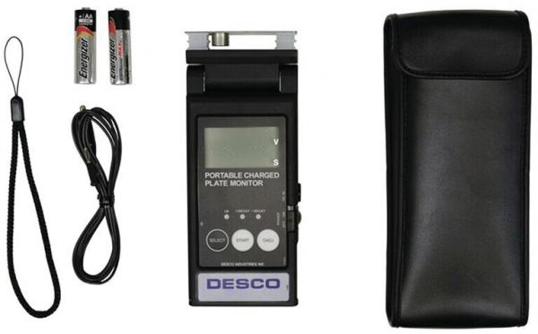 The image shows a portable device, a flat monitor with a digital display. Next to it are two batteries, a cable, and a black bag.