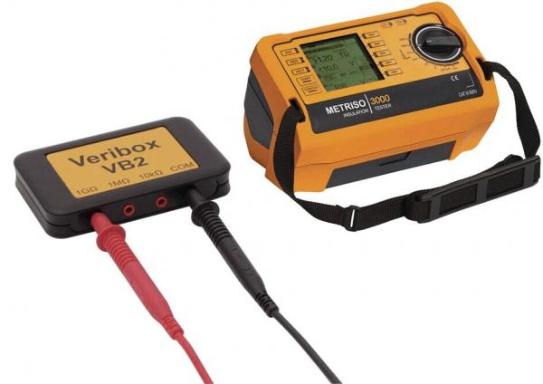 The image displays an orange measuring device with a screen and buttons, connected to a black box called "Veribox VB2". Red and black cables are attached.