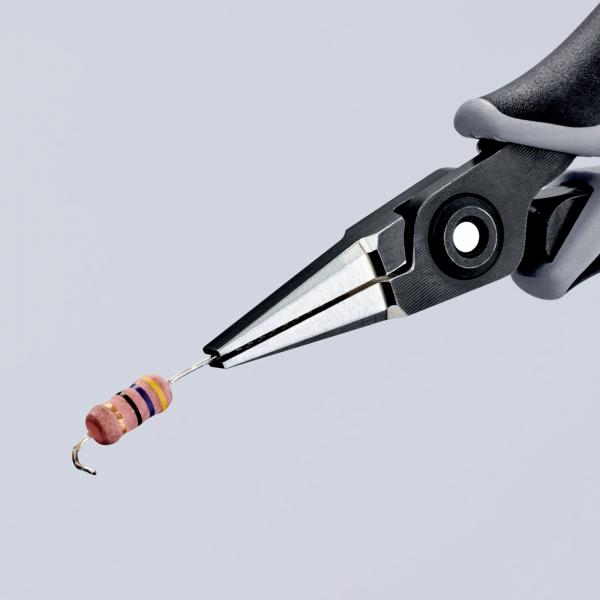 A pair of pliers is holding a resistor in the air. The resistor has colored stripes in pink, purple, and yellow. The background is light gray and neutral.