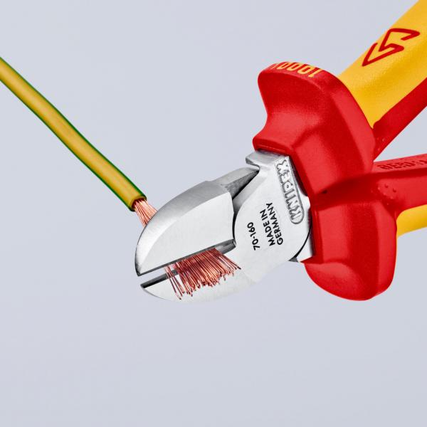 The image shows a pair of pliers with red and yellow grip areas, cutting a green wire. The blade is made of metal and is tightly applied to the wire.