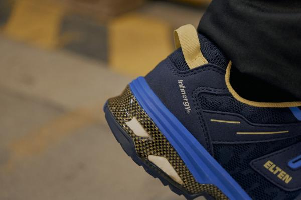 Das Bild zeigt einen nahen Ausschnitt eines Sportschuhs in Blau und Schwarz. Der Schuh hat gelbe Akzente und eine profilierte Sohle, die für guten Halt sorgt.