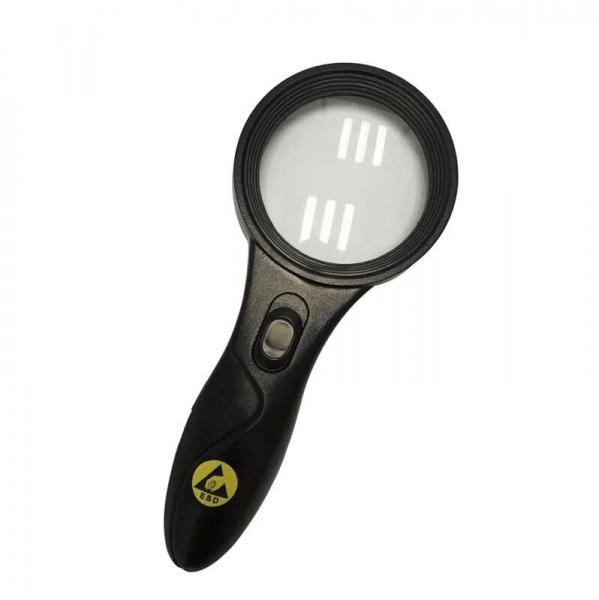 The image shows a black magnifying glass with a round lens and an ergonomic handle. There is a switch on the front to turn on the light.