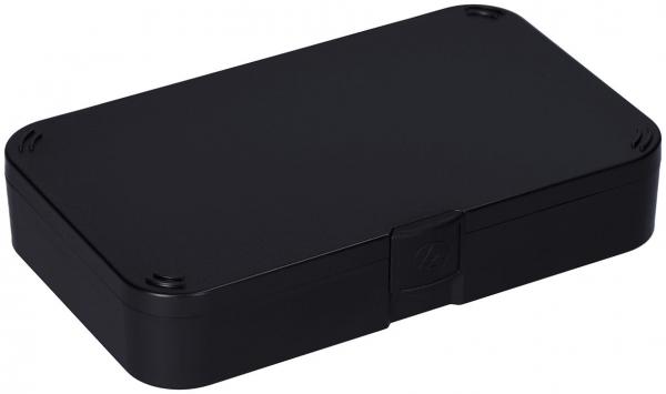 Das Bild zeigt eine rechteckige, schwarze Box. Sie hat abgerundete Ecken und eine flache Oberseite. An einer Seite befindet sich ein kleiner Verschluss oder Clip. Die Box wirkt robust und unauffällig.