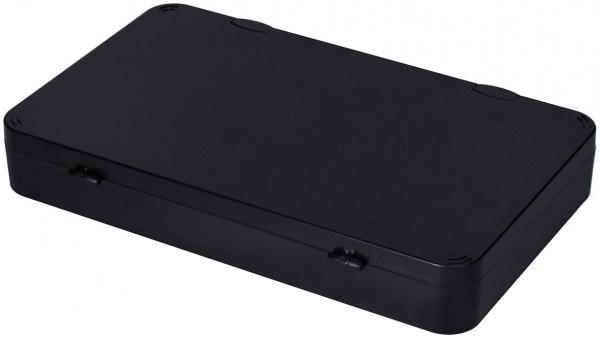 Das Bild zeigt eine flache, rechteckige Box in Schwarz. Die Oberseite ist glatt und hat runde Ecken. An den Seiten sind zwei kleine Vertiefungen sichtbar, wahrscheinlich zum Öffnen.