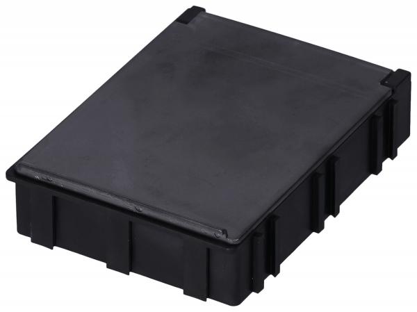 Das Bild zeigt eine rechteckige, flache Box aus schwarzem Kunststoff. Sie hat eine glatte Oberseite und seitliche Rillen oder Vertiefungen, die ihr Struktur verleihen.