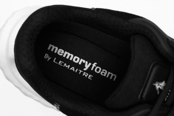 Das Bild zeigt die Innensohle eines Schuhs. Der obere Teil ist schwarz mit weißem Text, der "memoryfoam" und "By Lemaître" anzeigt. Der Schuh wirkt sportlich und modern.