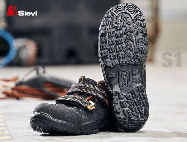 The image shows a pair of black safety shoes with a non-slip sole. The shoes have wide straps over the foot and are suitable for use in an industrial environment.
