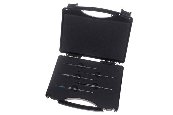 The image shows a black suitcase with an open flap. Inside, several long, thin tools are arranged in a row, lying on a soft, velvety surface.