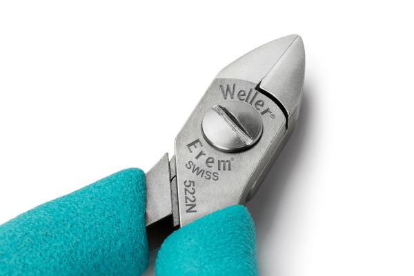 The image shows a small, metal pliers with a sharp cutting edge. The handle is green and non-slip. The brands and model numbers are engraved on the pliers.