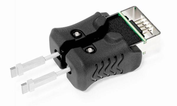 The image shows a black device with two side levers and a connection socket. It has an ergonomic shape and displays technical details for connecting or adjusting cables.