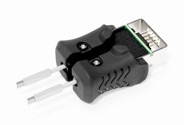 Das Bild zeigt einen schwarzen Stecker mit einer oberen rechteckigen Verbindung und zwei metallischen Stiften, die seitlich herausragen. Die Oberfläche ist gerippt und es gibt kleine Schrauben.